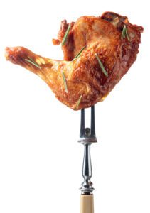 grilled seasoned chicken drumstick held up on fork